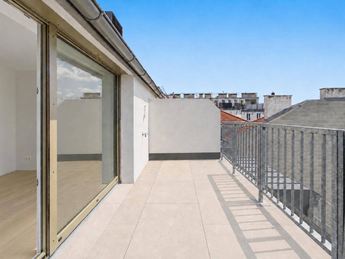 Helle, geflieste Dachterrasse mit Zugang zu Innenräumen und Blick auf die umliegenden Gebäude.