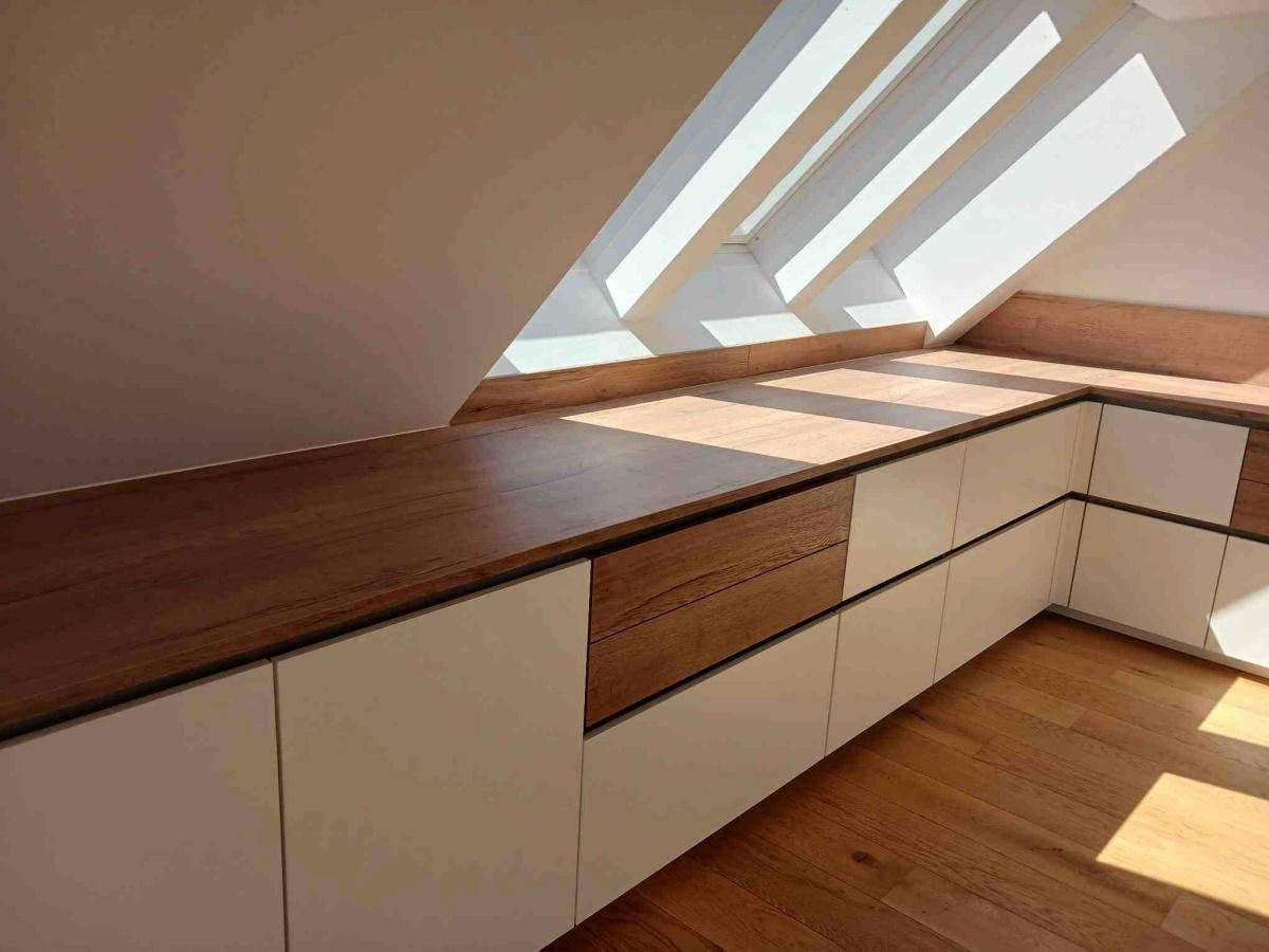 Detailansicht der modernen Einbauschränke mit Holzplatte und viel Stauraum im sonnigen Dachgeschoss.