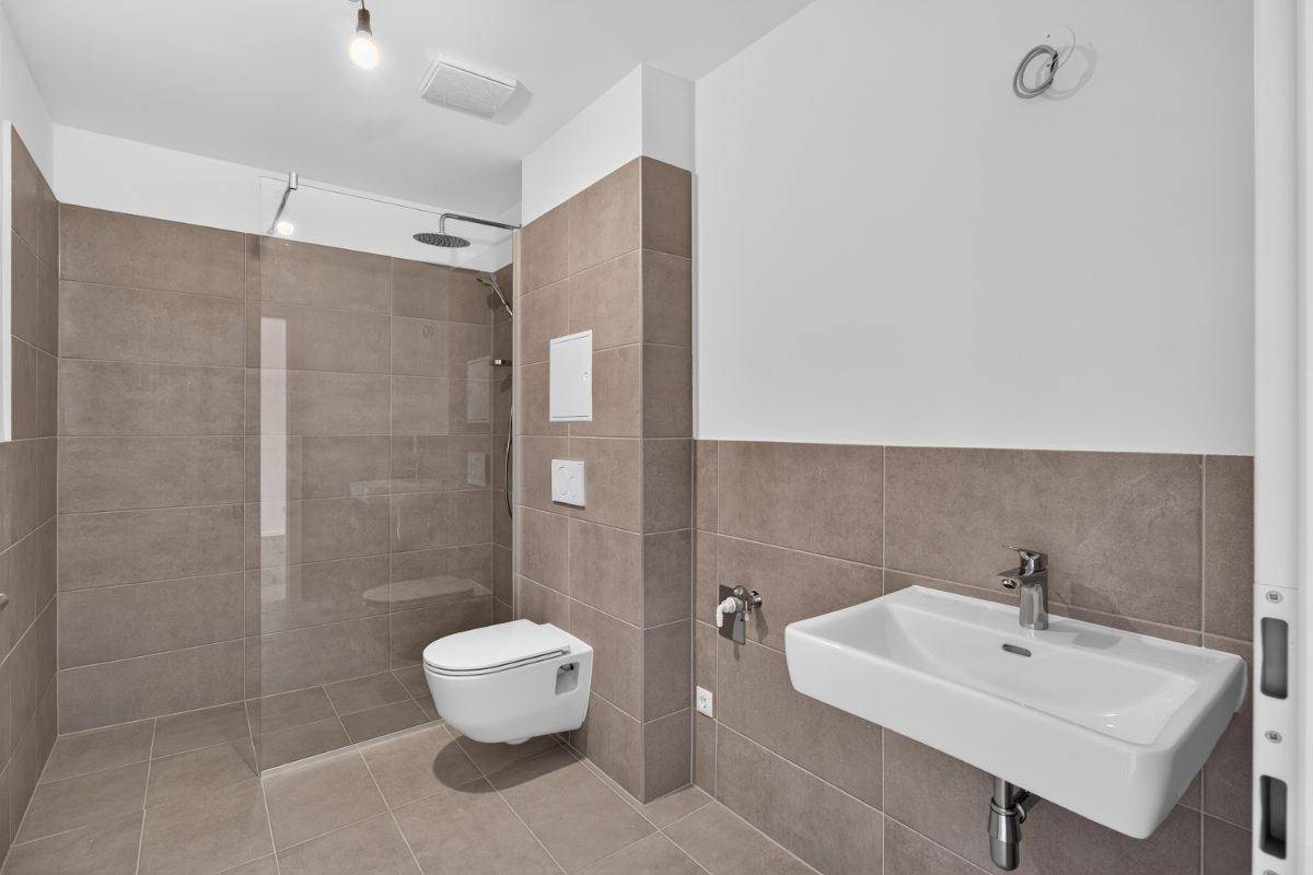 Modernes Badezimmer mit begehbarer Dusche, Wand-WC und großformatigen Fliesen.