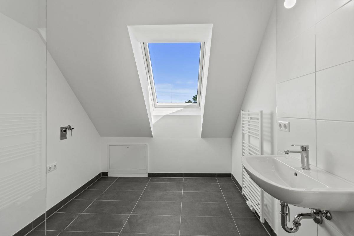 Helles Badezimmer mit Dachfenster, modernem Waschbecken und beheiztem Handtuchhalter.