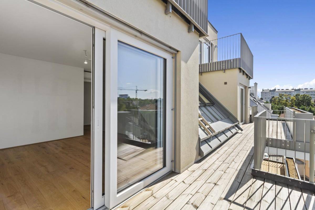 Sonnenverwöhnter Balkon mit Holzboden und weitem Blick über die Stadt.