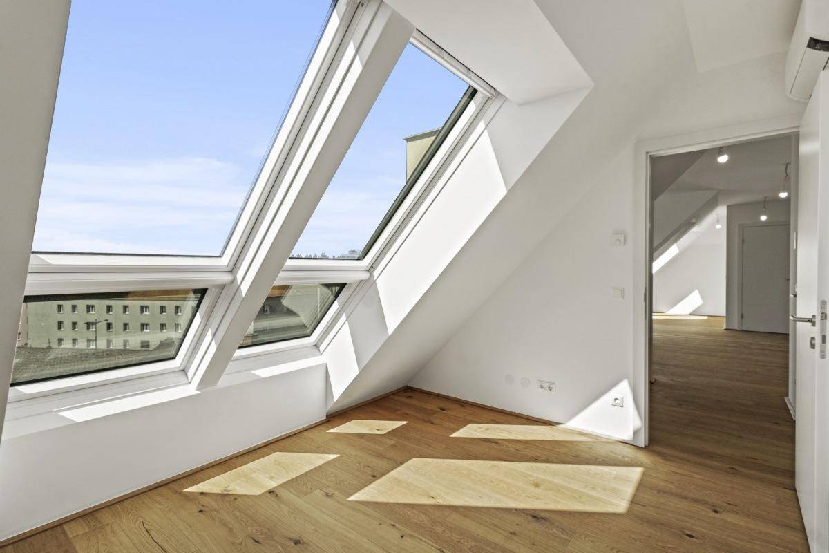 Heller Dachgeschossraum mit großen Dachfenstern, Holzboden und installierter Klimaanlage.