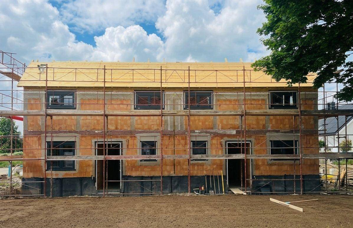 Neubau eines Mehrfamilienhauses in Massivbauweise mit Gerüst und sichtbaren Ziegeln.