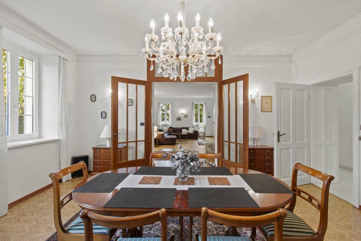Eleganter Essbereich mit Holztisch, Stühlen und einem opulenten Kronleuchter.