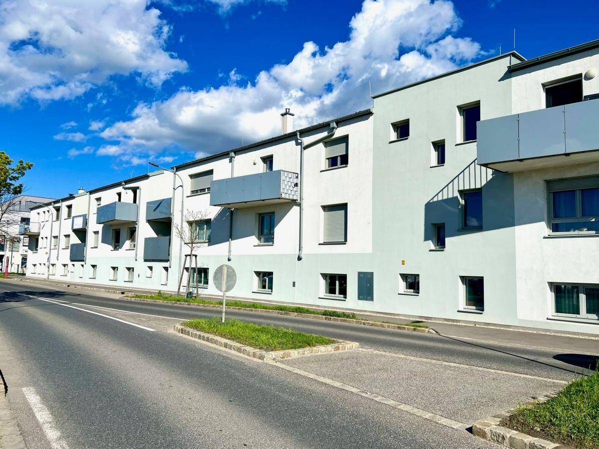 Ansicht der modernen Wohngebäude mit weißer und hellgrauer Fassade sowie Balkonen an einer Straße.