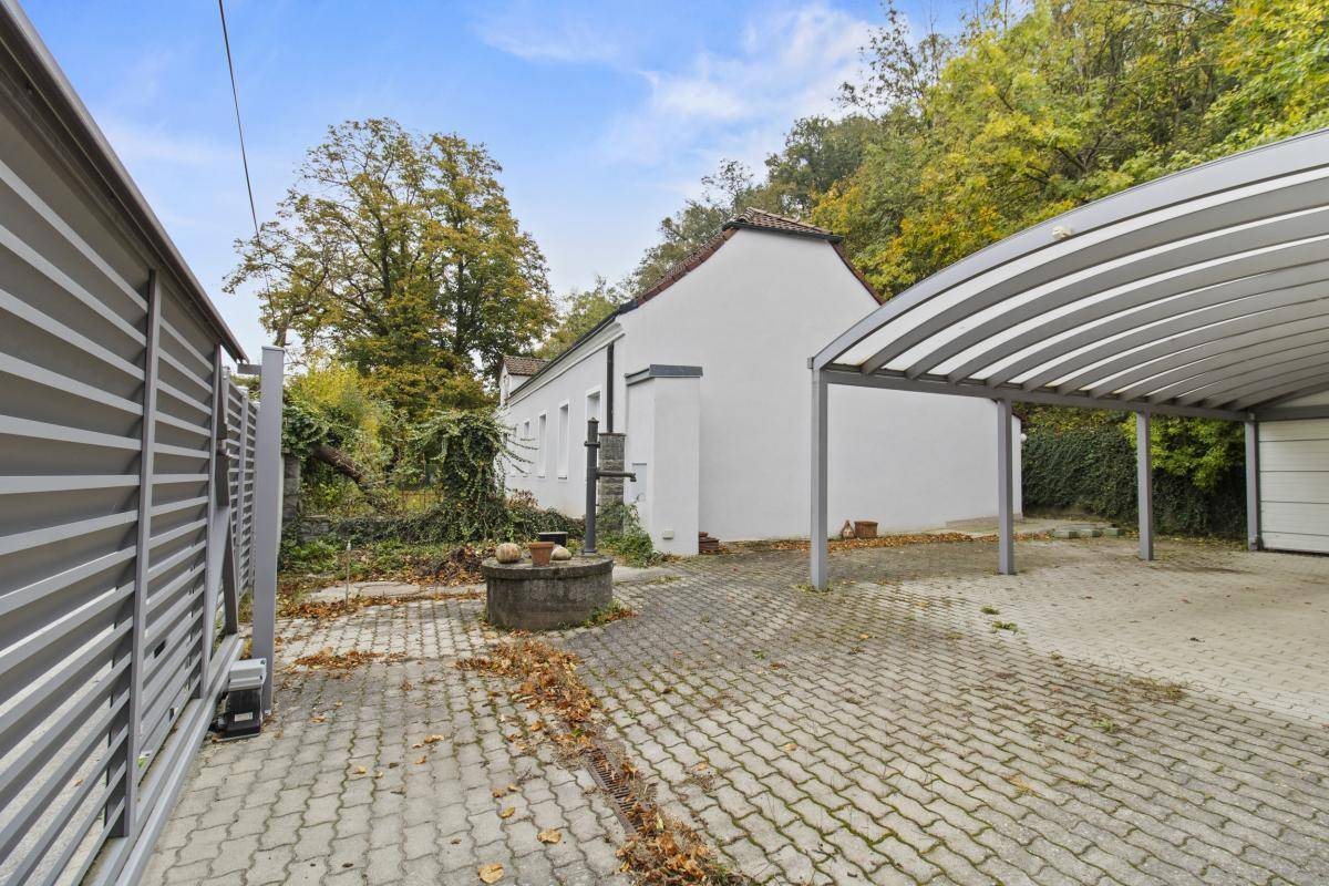 Einfahrt mit Carport und Seitenansicht des Hauses in ländlicher Umgebung.