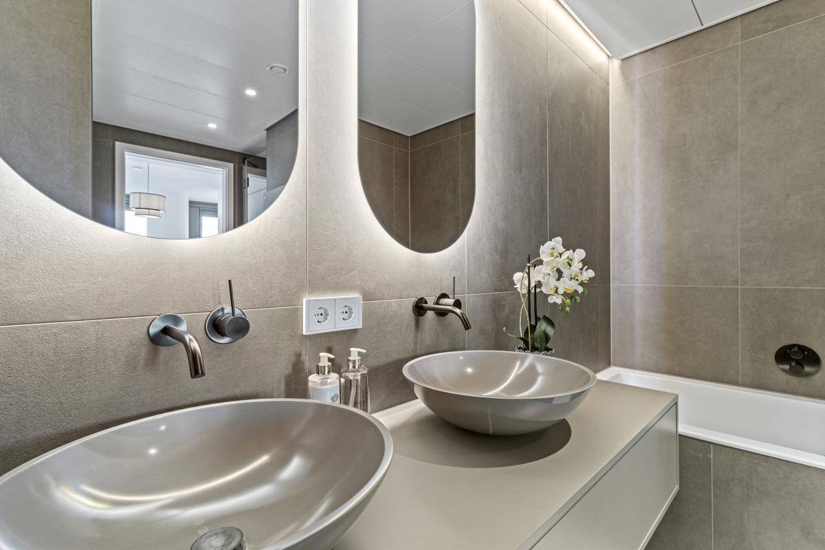 Detailansicht des modernen Doppelwaschbeckens mit stilvollen Armaturen und beleuchteten Spiegeln.