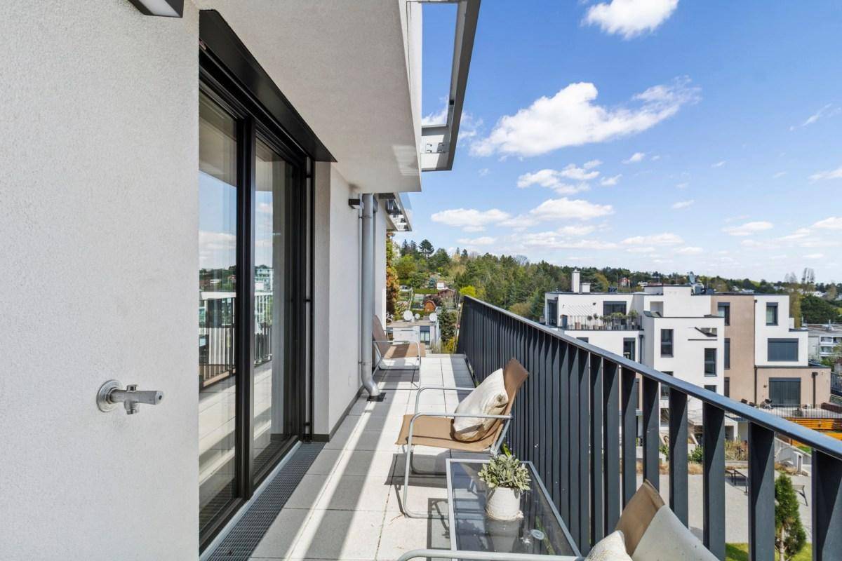 Geräumiger Balkon mit Sitzgelegenheiten und weitem Blick über die moderne Wohnanlage.