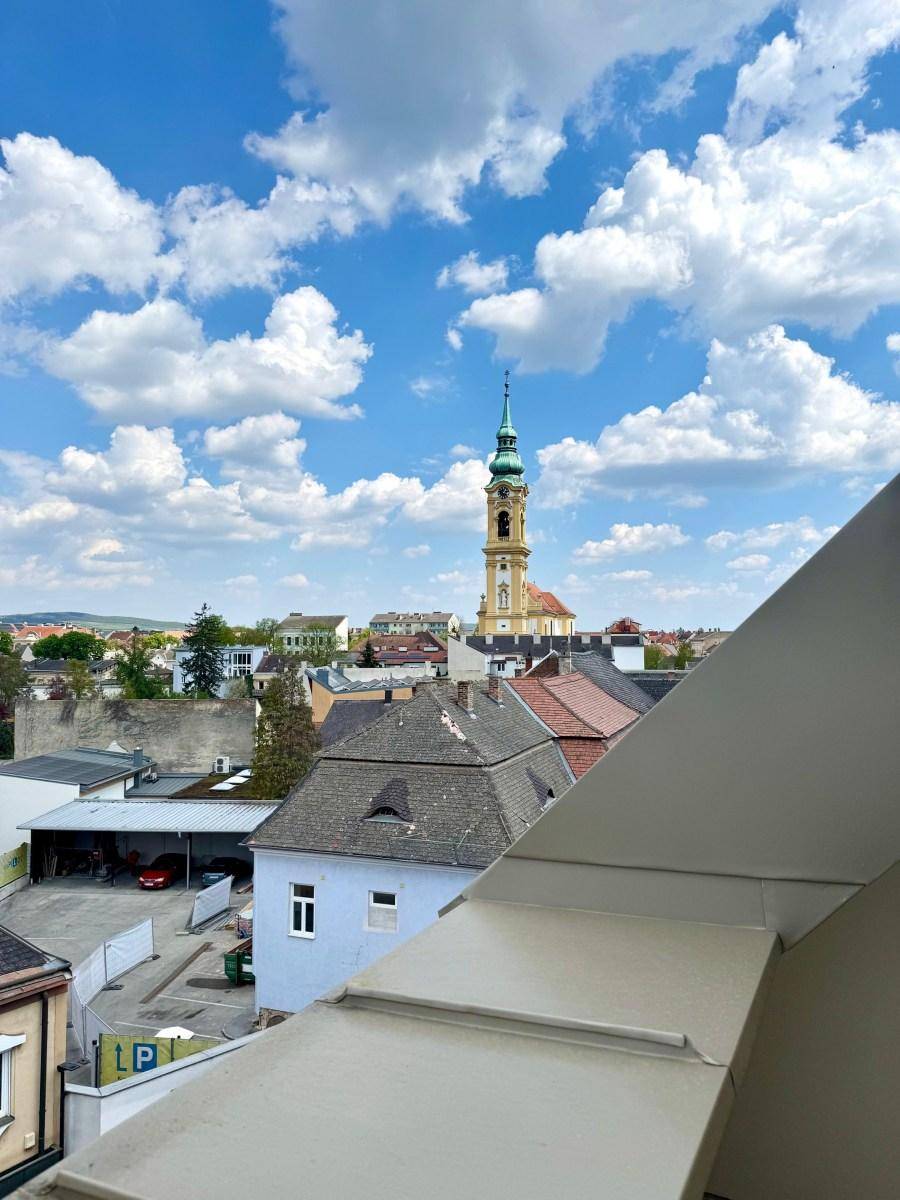 Panoramablick über die Stadt mit historischem Kirchturm unter blauem Himmel.