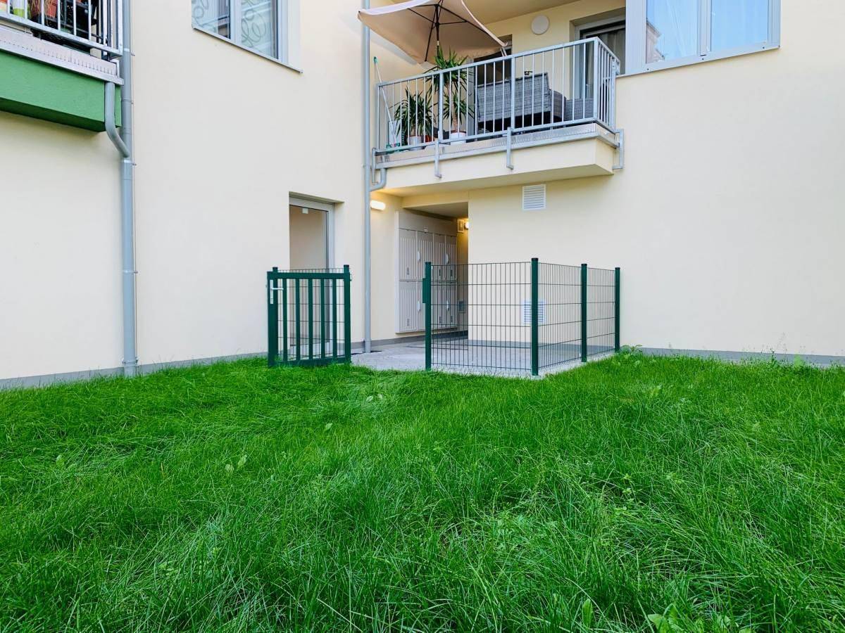 Kleiner privater Gartenbereich mit Rasenfläche und Zugang zu einer Terrasse.