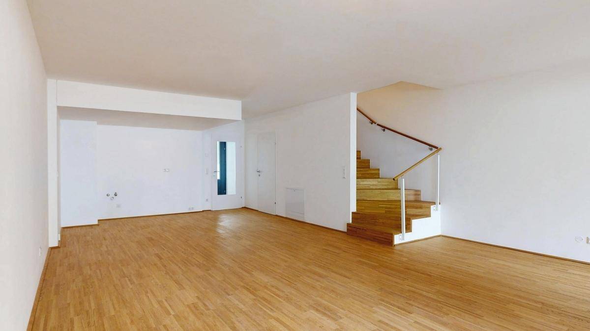 Heller Wohnbereich mit Holztreppe und Parkettboden, bereit für individuelle Gestaltung.