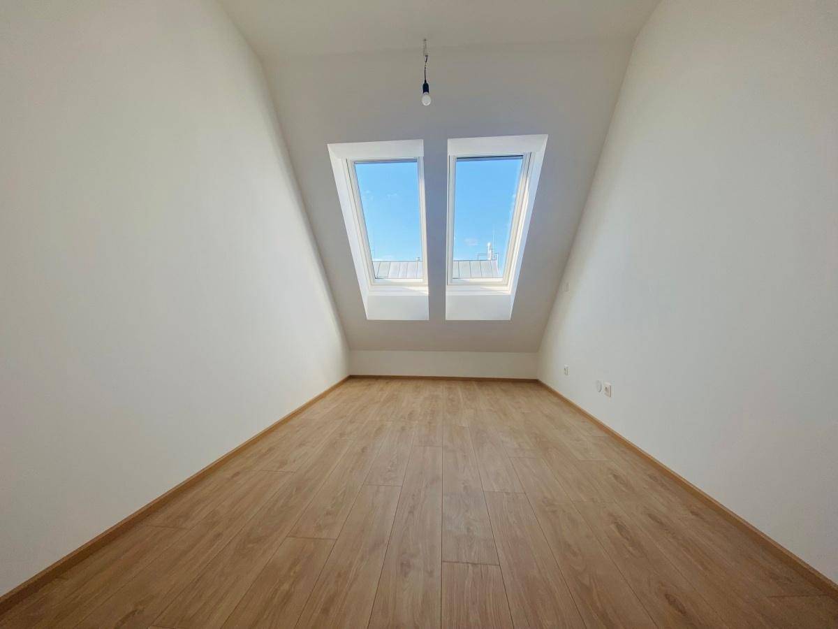 Schlafzimmer mit Laminatboden, Dachschrägen und zwei Dachfenstern für helles Ambiente.