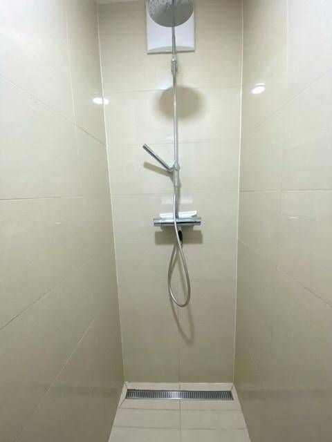 Moderne begehbare Dusche mit Regenduschkopf und großformatigen Fliesen in hellem Beige.