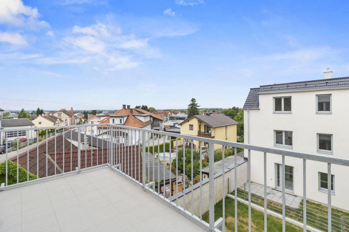 Großer Balkon mit Fliesenboden und weitem Blick über die Dächer der umliegenden Häuser.