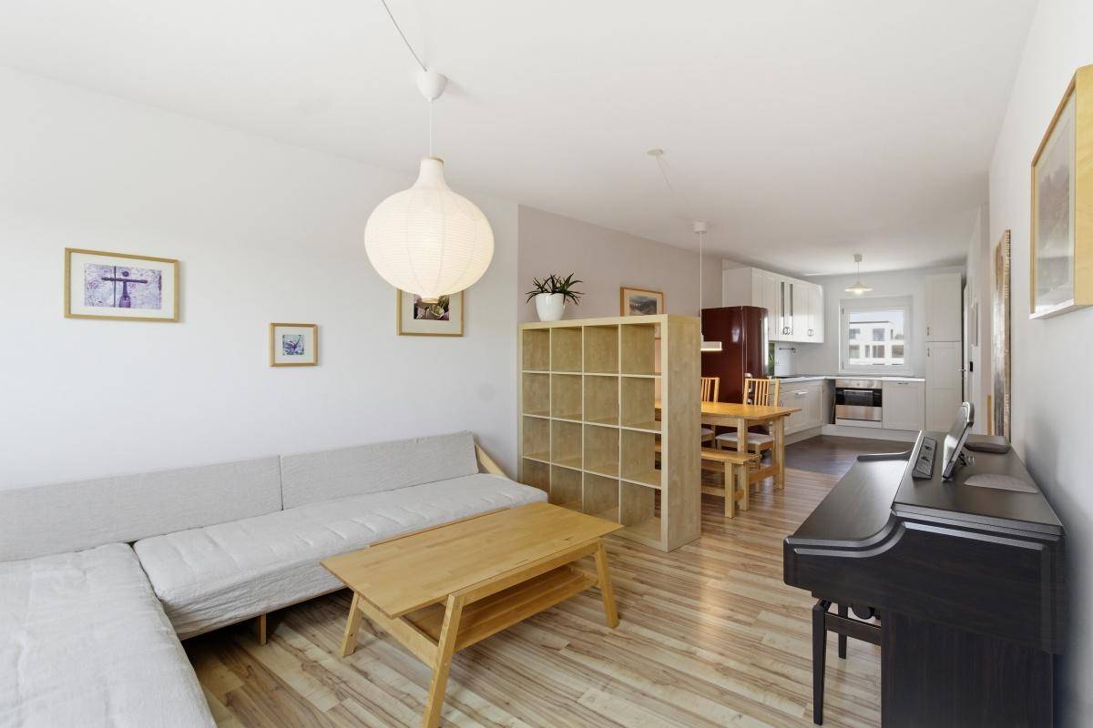 Gemütlicher Wohnbereich mit großem Sofa, Couchtisch und Klavier, offen zum Ess- und Küchenbereich.