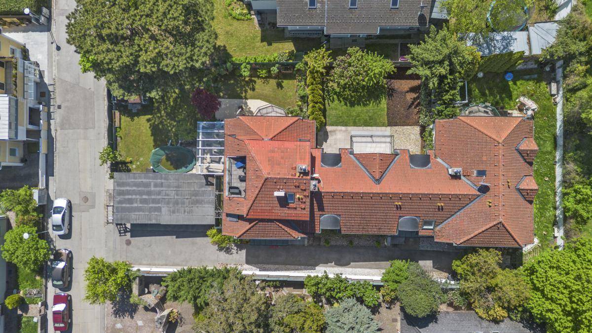 Draufsicht auf das Anwesen mit rotem Ziegeldach, Garten und umliegenden Straßen und Häusern.