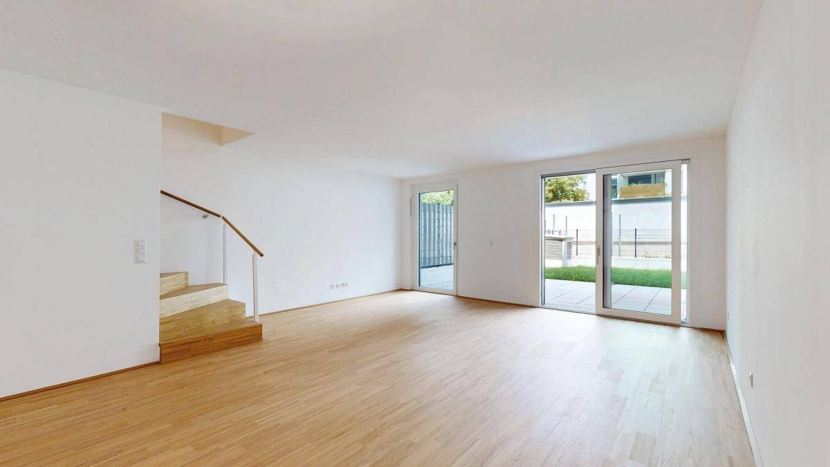 Heller Wohnbereich mit Treppenzugang und großen Fenstern zur Terrasse und Garten.