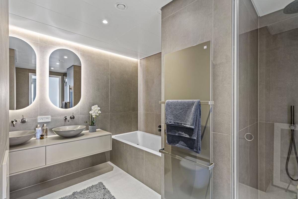 Modernes Badezimmer mit Badewanne, Dusche, Doppelwaschbecken und beheiztem Handtuchhalter.
