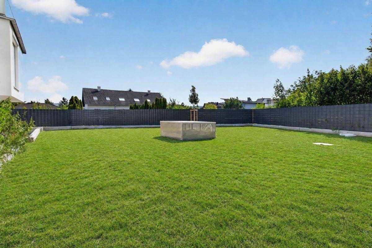 Große, gepflegte Rasenfläche im Gartenbereich, umgeben von einem modernen Zaun.