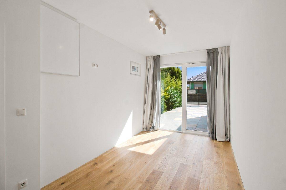Helles Schlafzimmer mit Holzboden und Zugang zur Terrasse oder zum Garten.