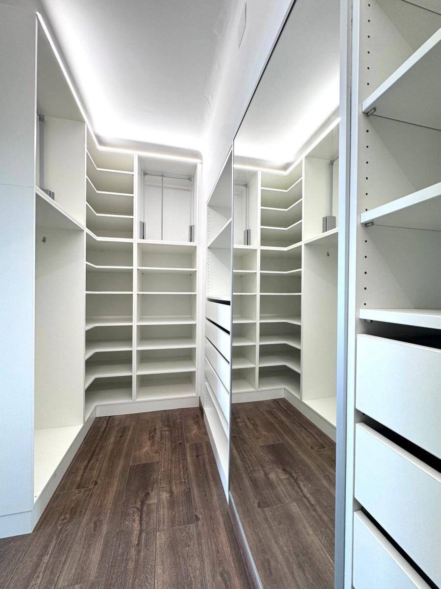 Geräumiger begehbarer Kleiderschrank mit vielen Regalen und einem großen Spiegel.