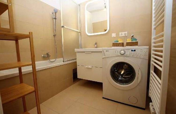 Modernes Badezimmer mit Badewanne, Waschmaschine und beheiztem Handtuchhalter.