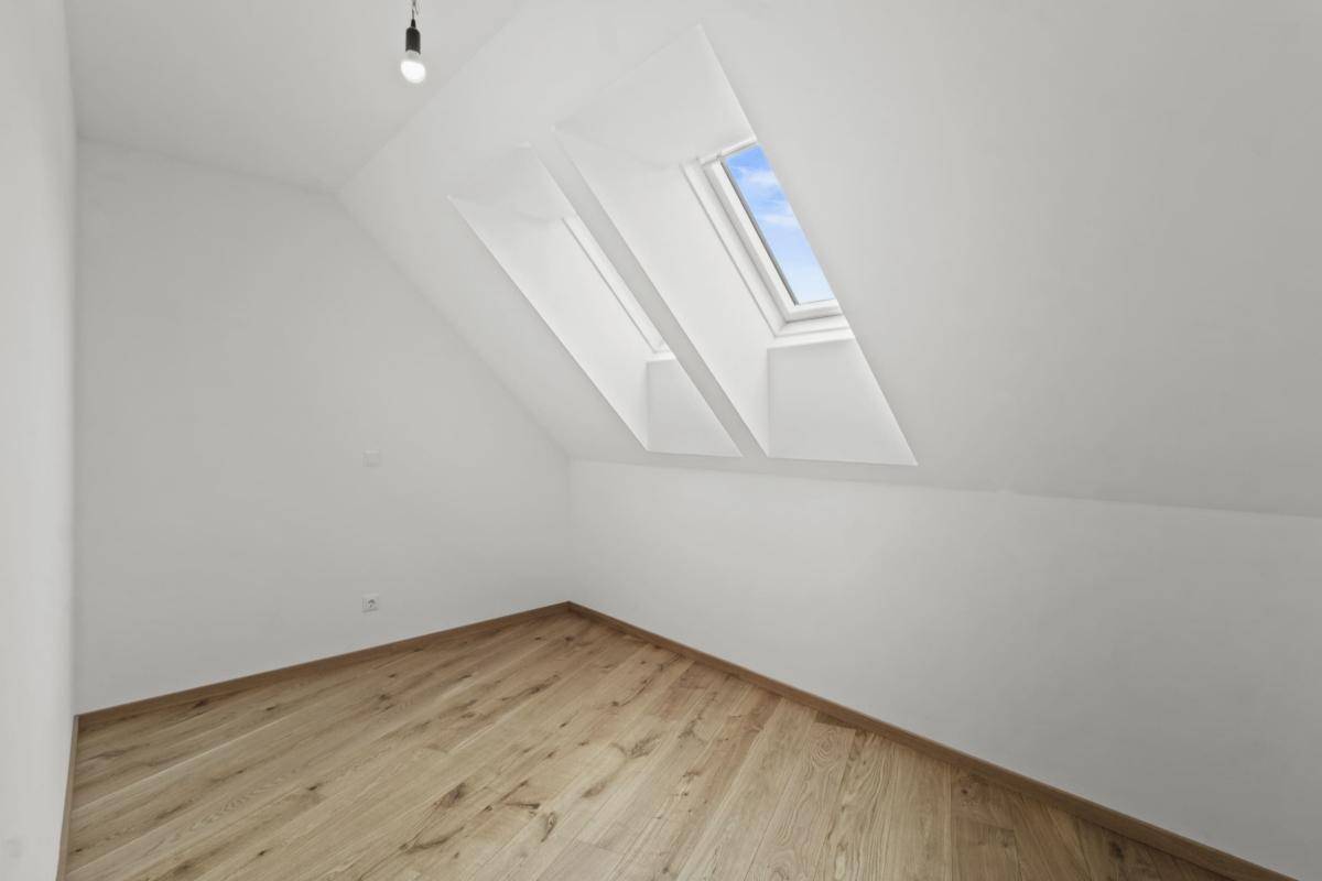 Helles Zimmer mit Holzboden, Dachschräge und einem Dachfenster, ideal als Kinderzimmer.