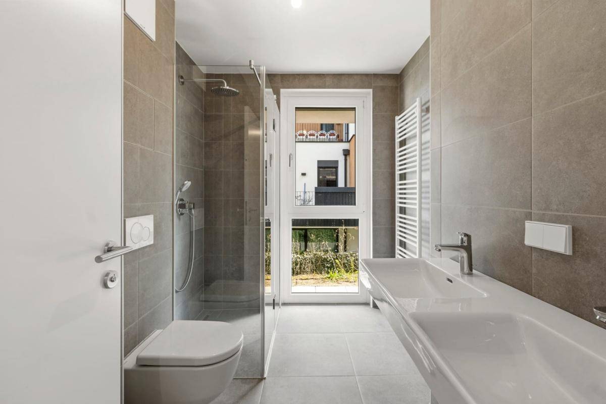 Modernes Badezimmer mit großformatigen Fliesen, Doppelwaschbecken und ebenerdiger Dusche.
