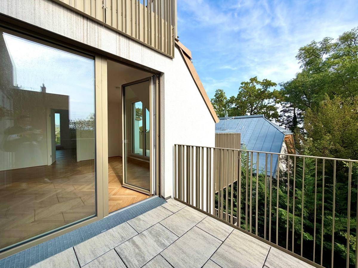 Moderner Balkon mit Fliesenboden und vertikalem Metallgeländer, angrenzend an ein Zimmer.