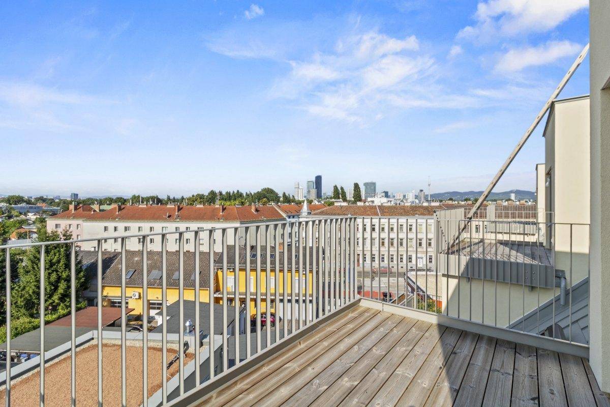 Geräumiger Balkon mit Holzboden und weitem Blick über die Stadt und Umgebung.
