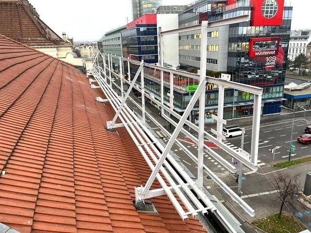 Dachansicht mit roten Ziegeln und Blick auf moderne Gebäude in der Ferne.