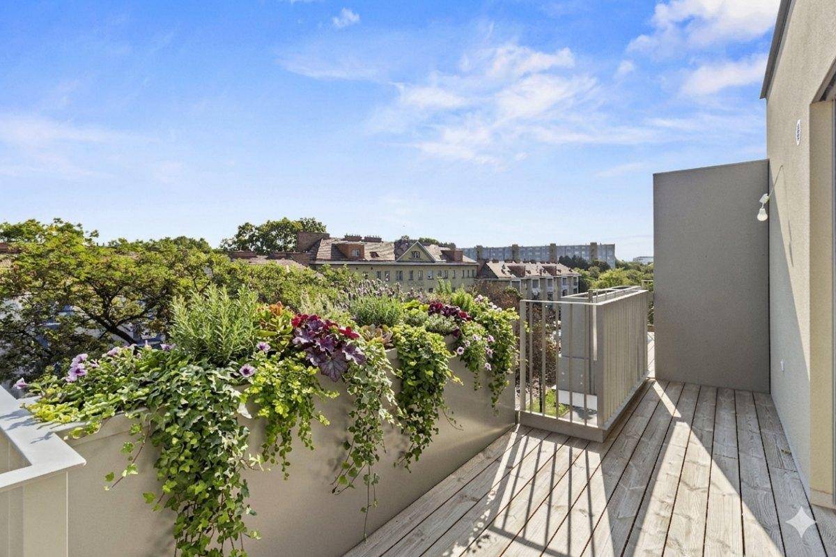 Sonniger Balkon mit Holzbelag, üppigen Pflanzen und weitem Blick über die Stadt.