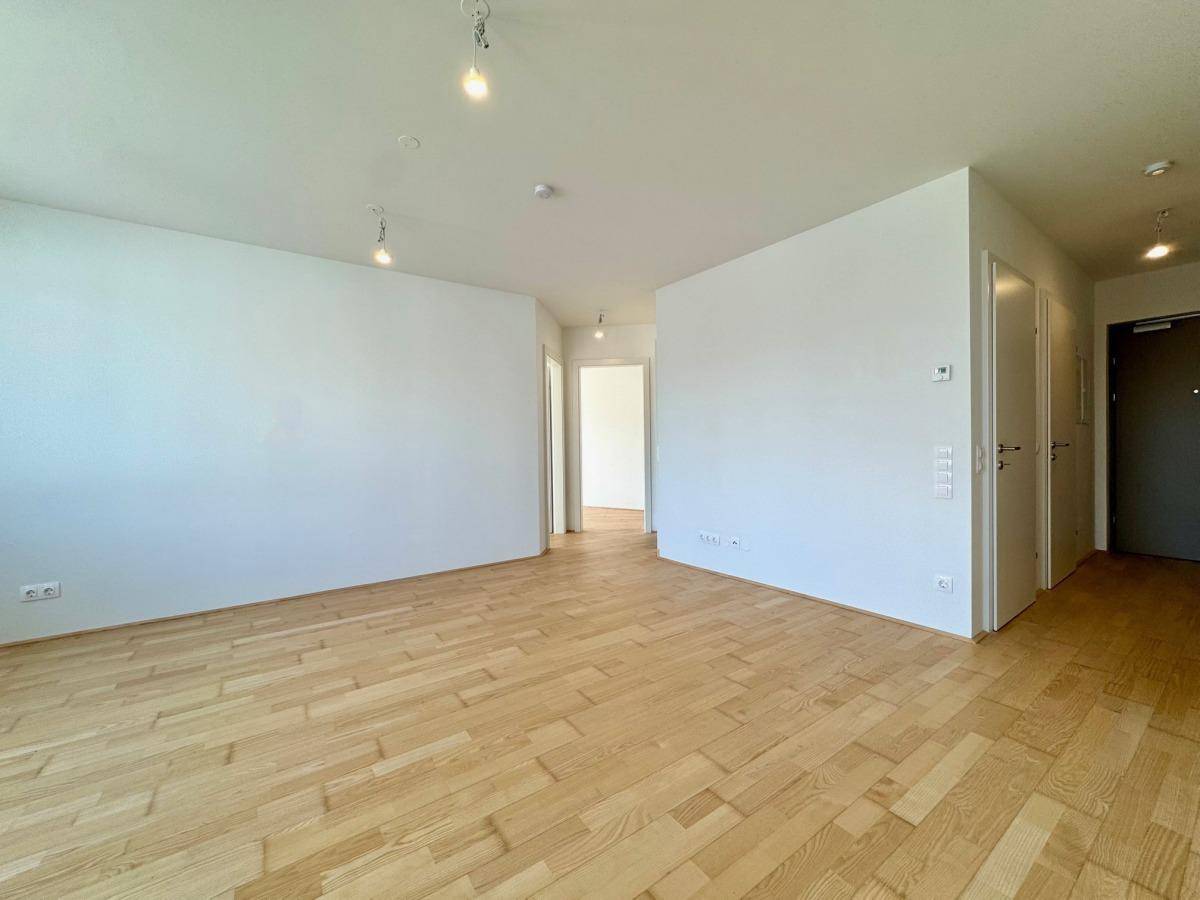 Heller Flur mit Parkettboden, der zu den verschiedenen Zimmern der Wohnung führt.