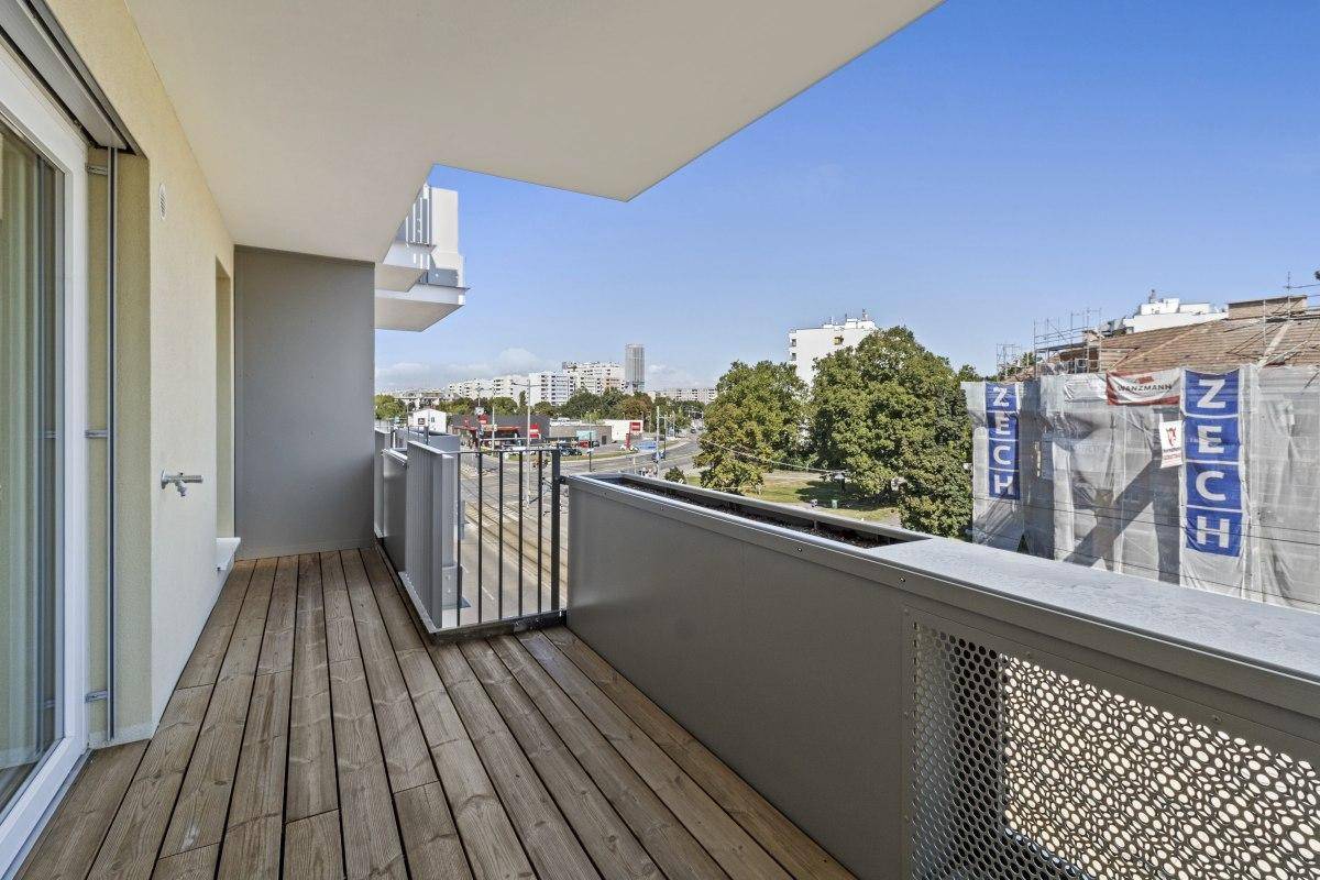 Langer Balkon mit Holzboden und Blick auf die Straße sowie umliegende Gebäude.
