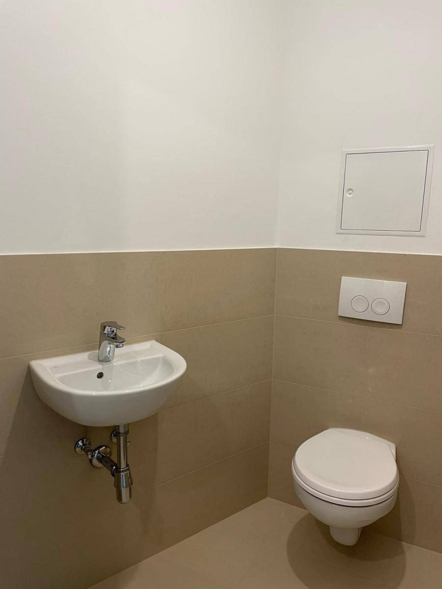 Gäste-WC mit wandhängender Toilette und kleinem Handwaschbecken.
