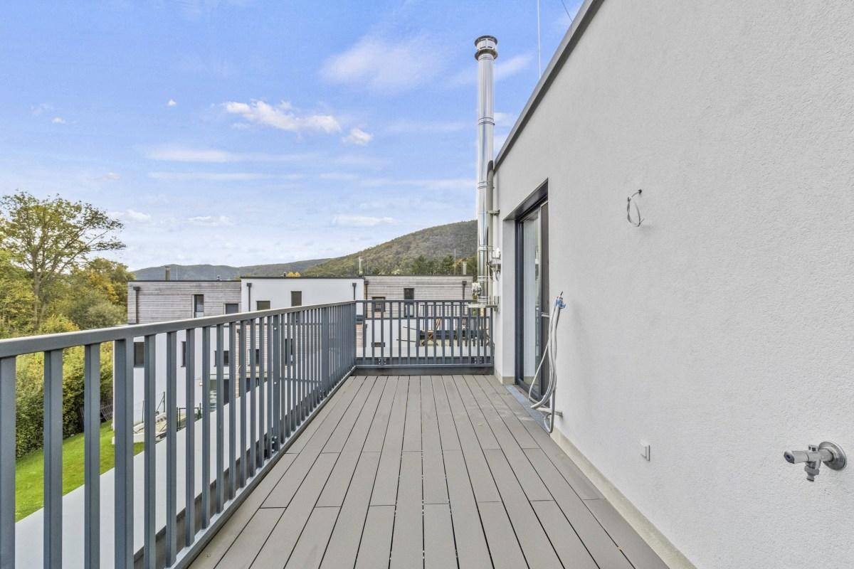 Langer Balkon mit modernem Geländer und Blick auf die umliegenden Häuser und Natur.