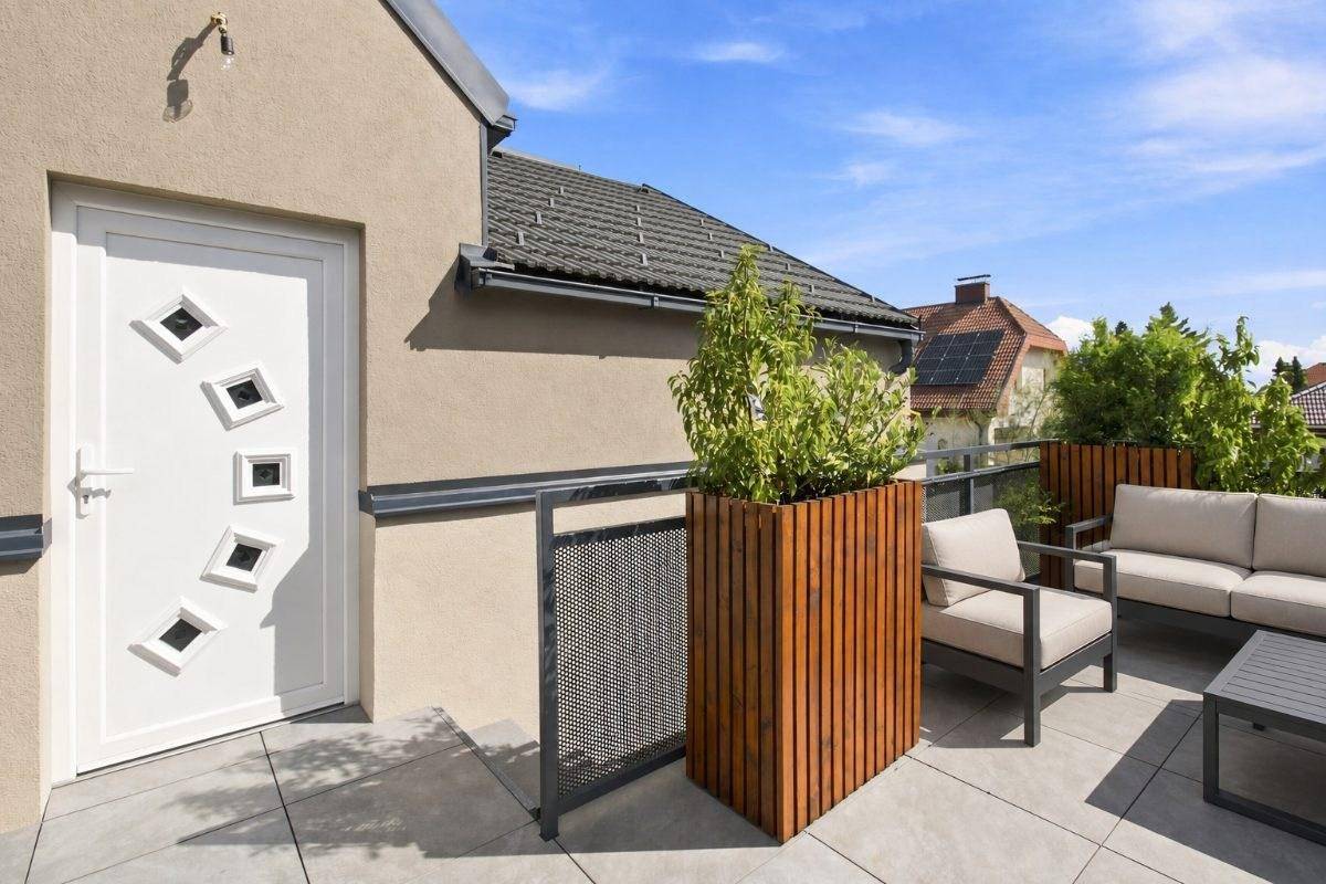 Sonniger Dachterrassenbereich mit Sitzgelegenheiten und dekorativen Pflanzenkübeln.