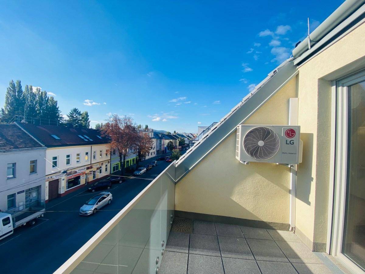 Sonniger Balkon mit Fliesenboden und weitem Blick über die umliegende Stadtlandschaft.