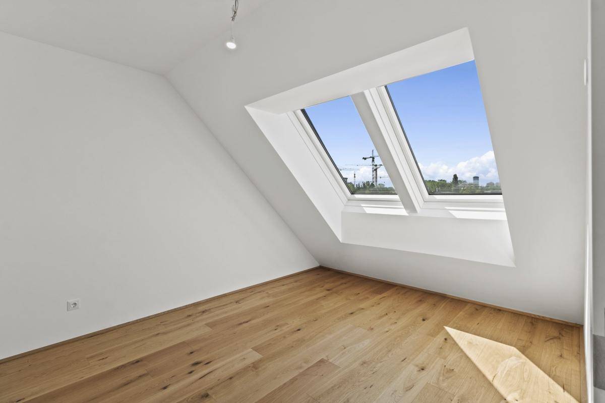 Lichtdurchflutetes Zimmer mit Holzboden und großem Dachfenster für viel Tageslicht.