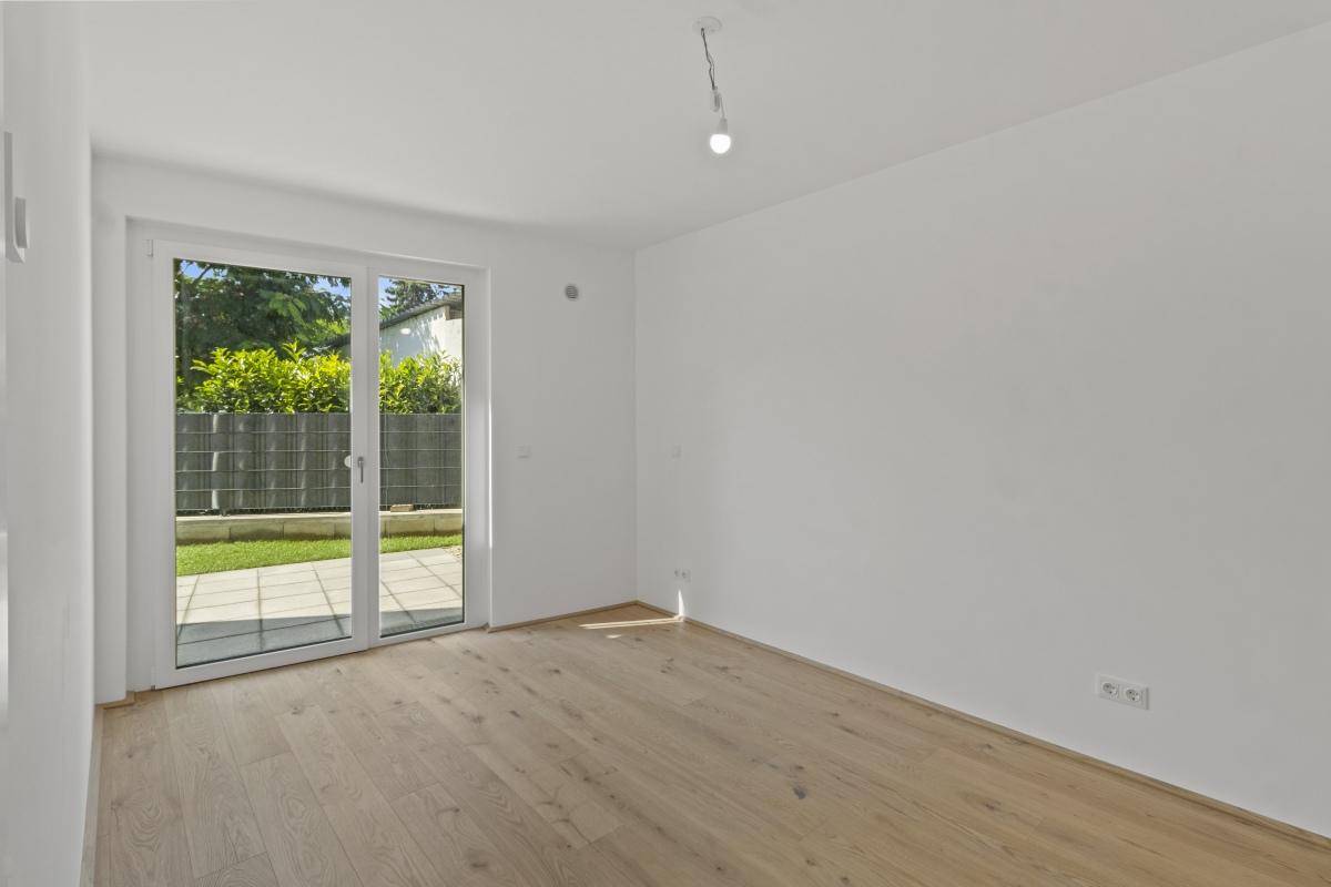 Helles Zimmer mit Parkettboden und Zugang zu einer Terrasse, ideal für entspannte Stunden.