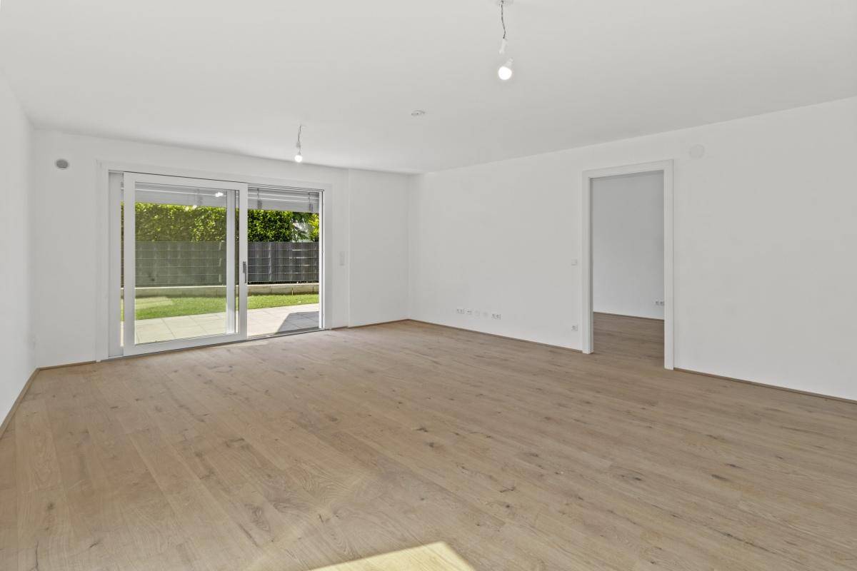 Geräumiger, heller Wohnbereich mit Parkettboden und direktem Zugang zur grünen Gartenfläche.