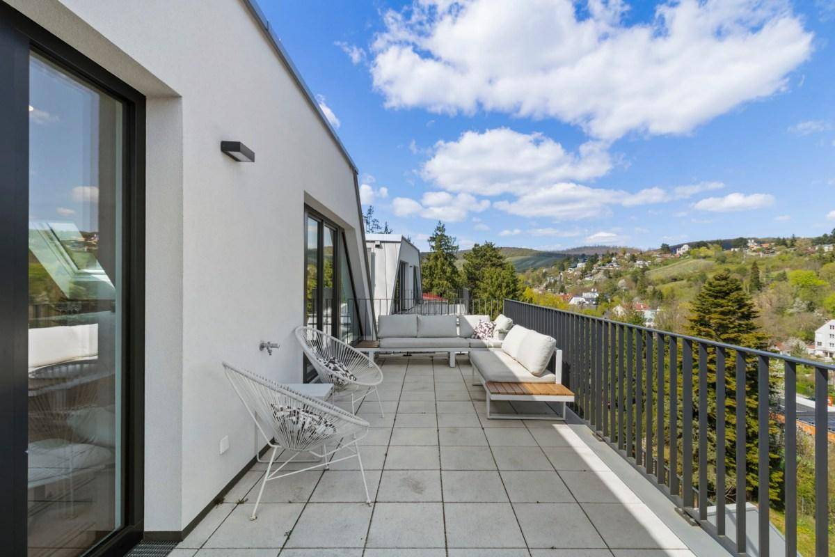 Große Terrasse mit modernen Gartenmöbeln und Panoramablick auf die grüne Umgebung und Stadt.