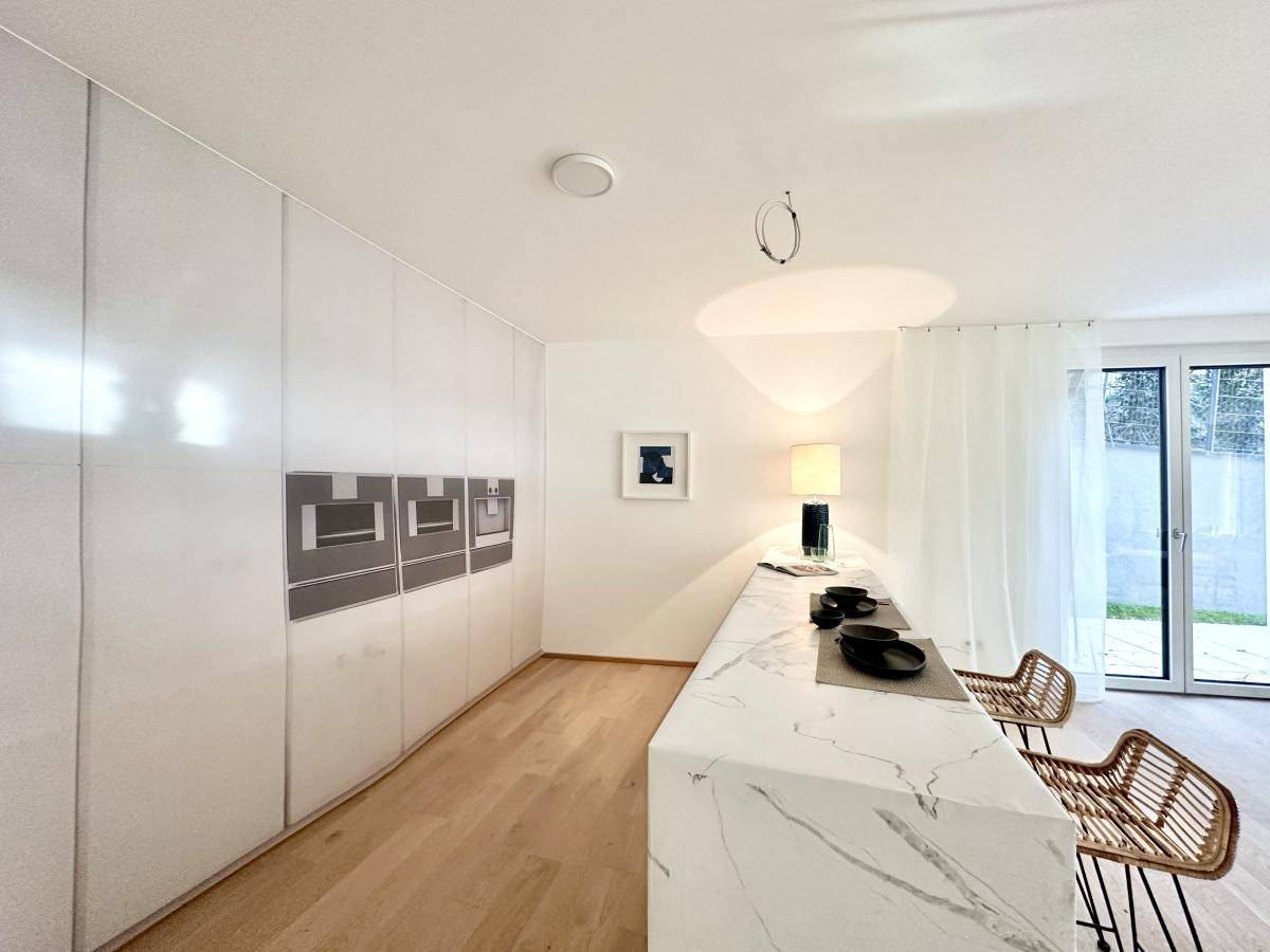 Moderne Küche mit glänzenden weißen Schränken, integrierten Geräten und Holzboden.