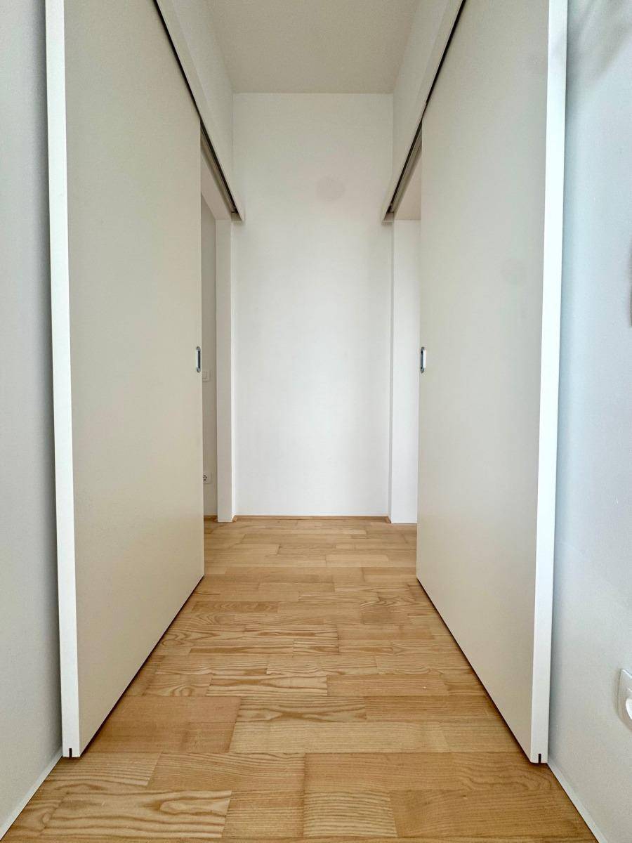 Heller Flur mit Holzparkettboden und modernen Schiebetüren, die zu den angrenzenden Räumen führen.