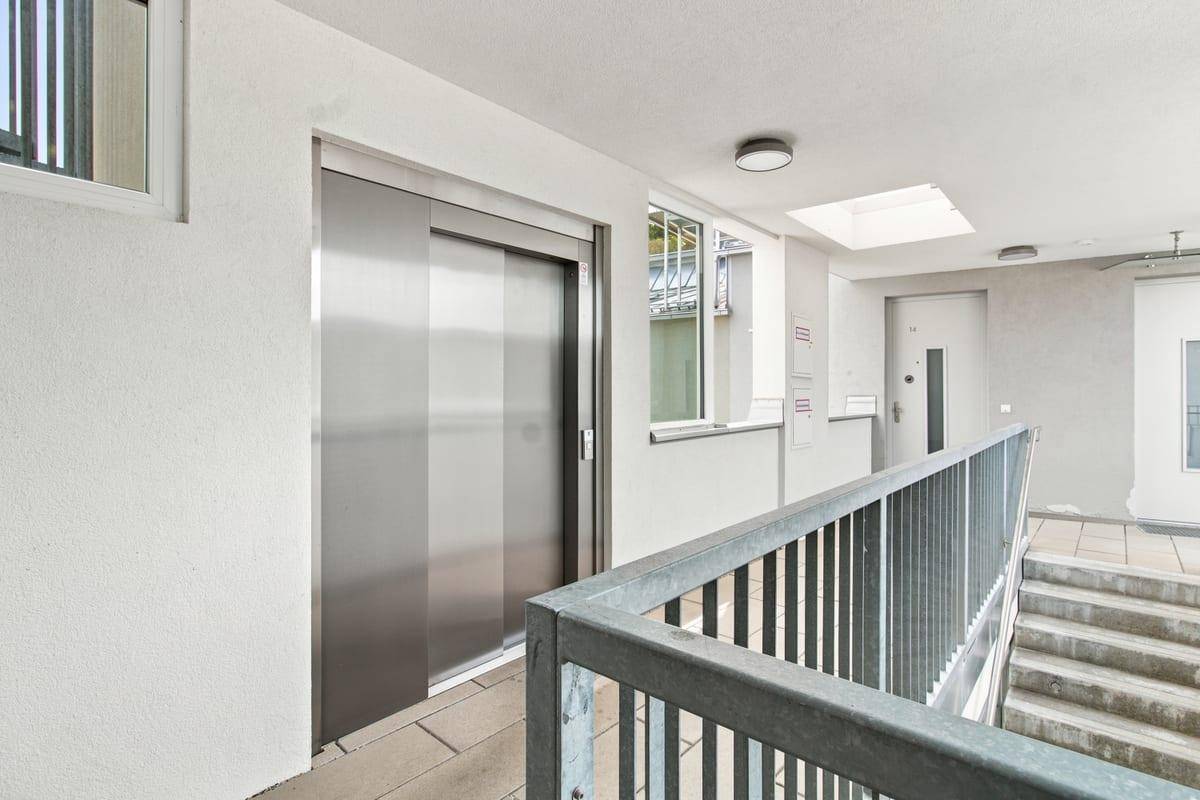 Heller Eingangsbereich mit Aufzug und Treppe, der zu den Wohneinheiten führt.