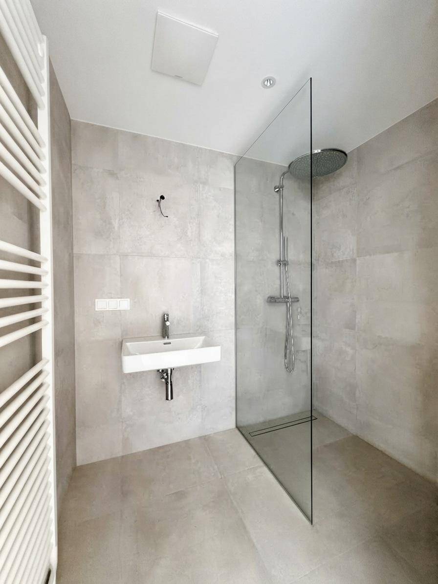 Zeitgemäßes Badezimmer mit ebenerdiger Dusche, Einzelwaschbecken und großformatigen Fliesen.