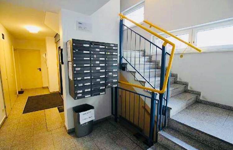 Eingangsbereich eines Mehrfamilienhauses mit Briefkästen und Treppenhaus.