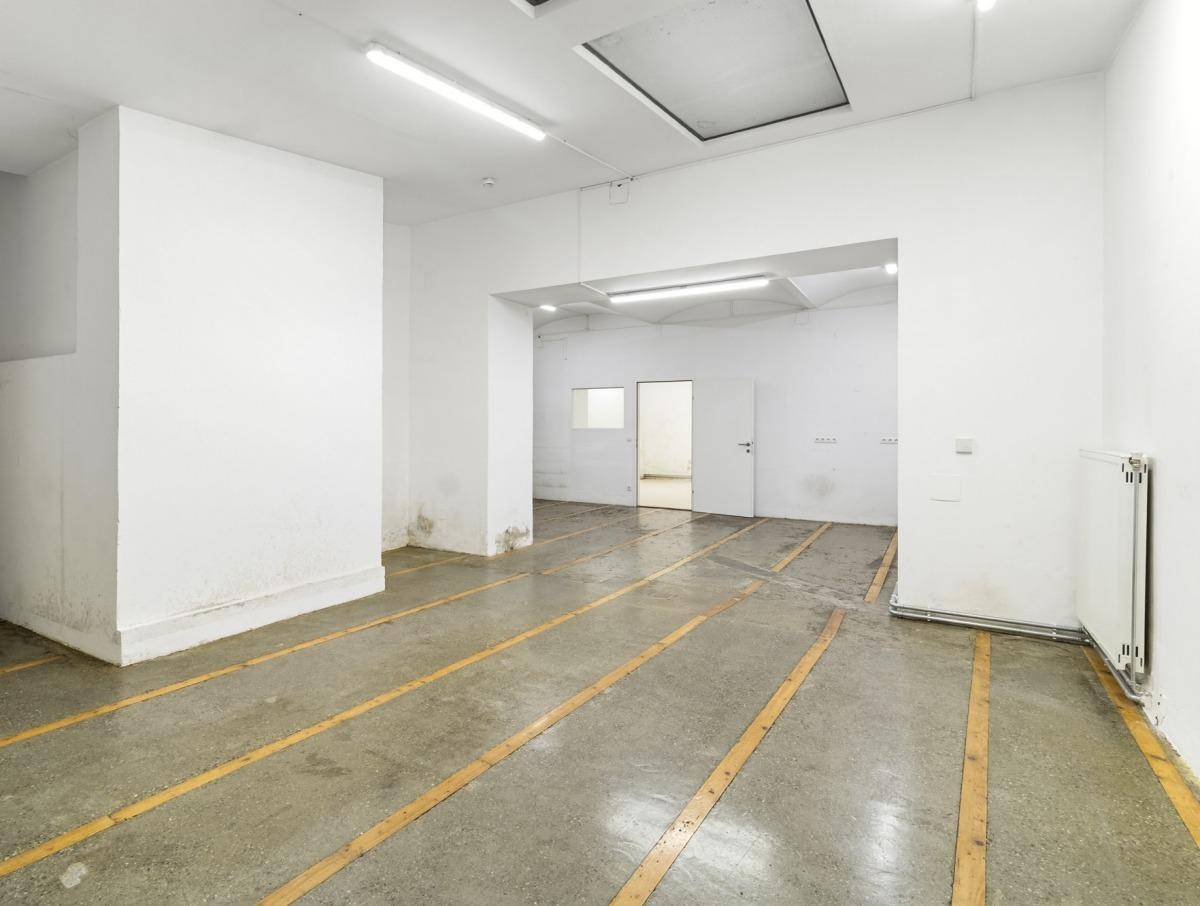 Großer, leerer Gewerberaum mit Betonboden und gelben Markierungen, ideal für Lager oder Werkstatt.