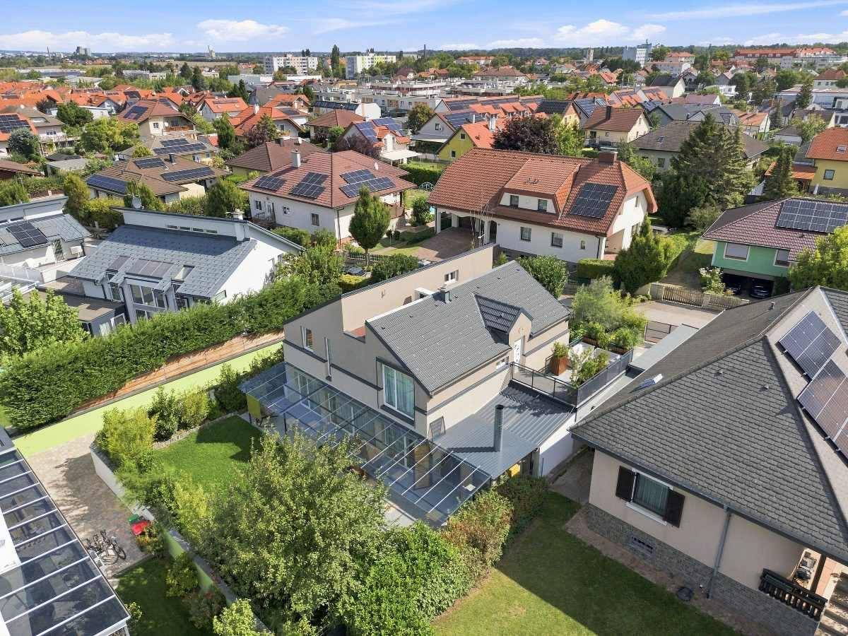 Vogelperspektive des Hauses mit Glasdach und Solaranlagen in einer grünen Wohnumgebung.