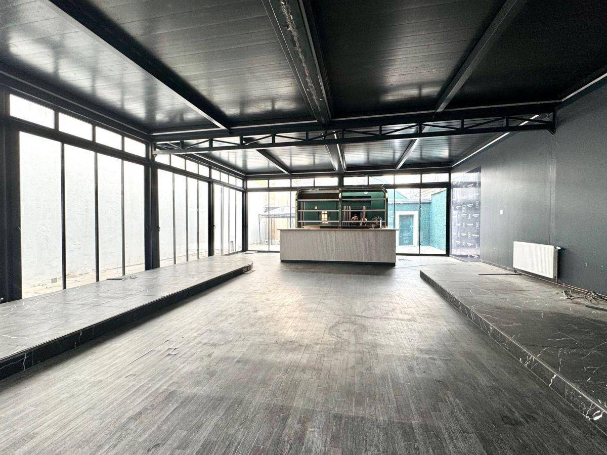 Großer, offener Gewerberaum mit moderner Bar, hohen Decken und großen Fensterfronten.